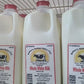 Bottles of Baker's Golden Dairy whole white milk on a shelf.