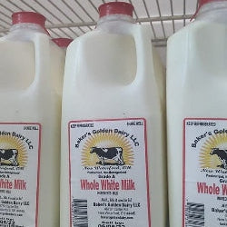 Bottles of Baker's Golden Dairy whole white milk on a shelf.